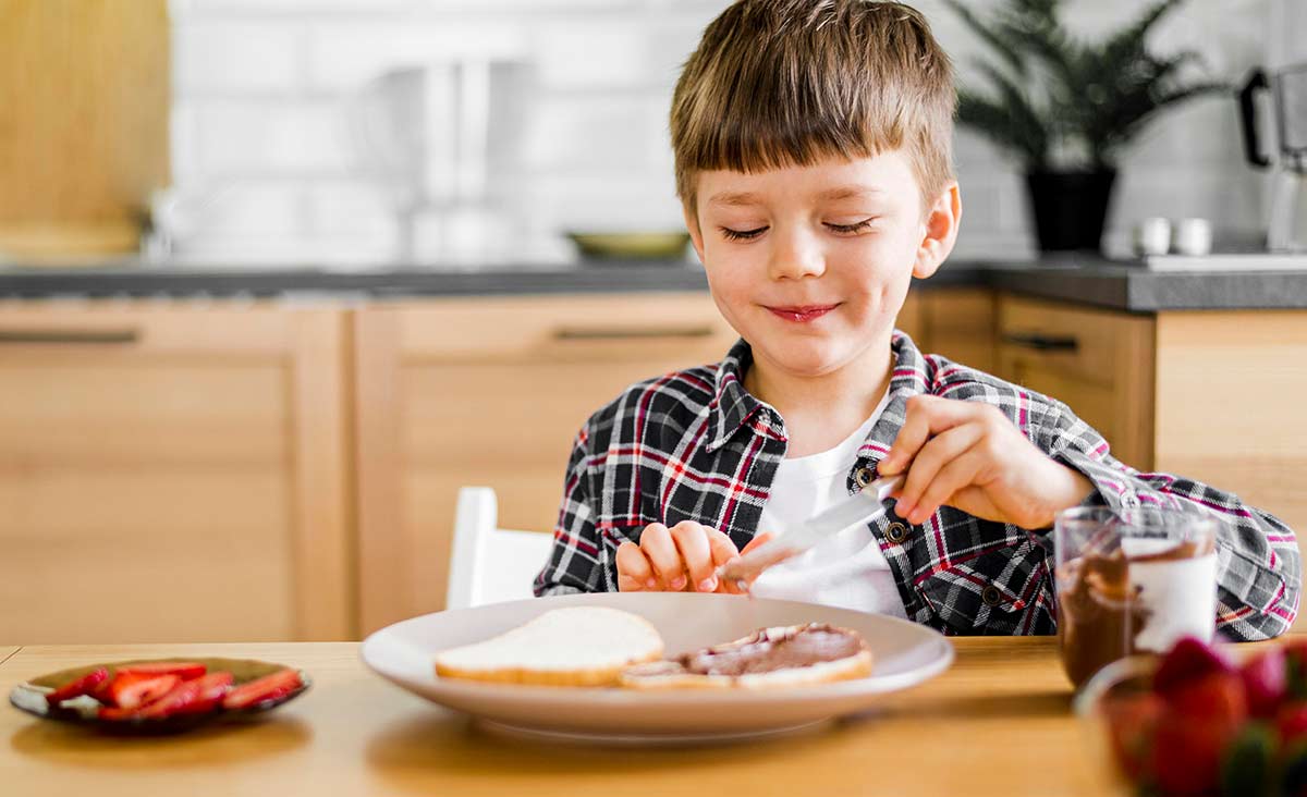 Kind benutzt Messer zum Brot schmieren
